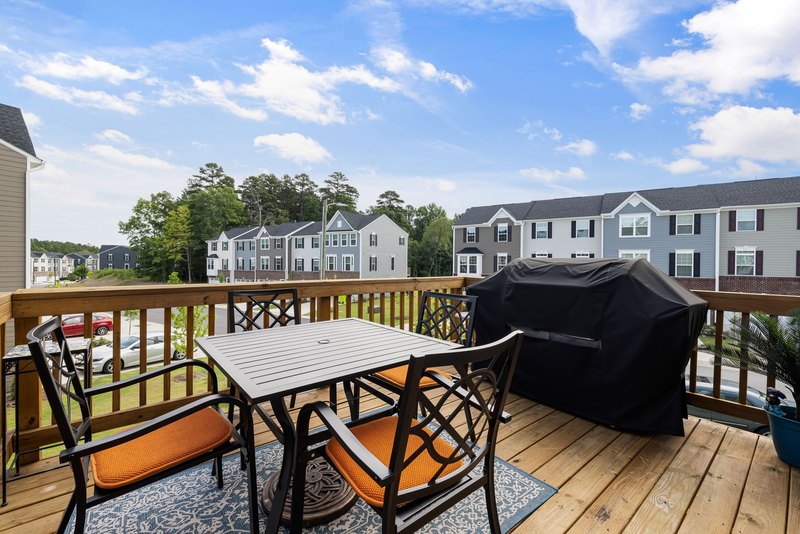 Wood deck railings and balusters around a table and a covered grill on a second-story deck