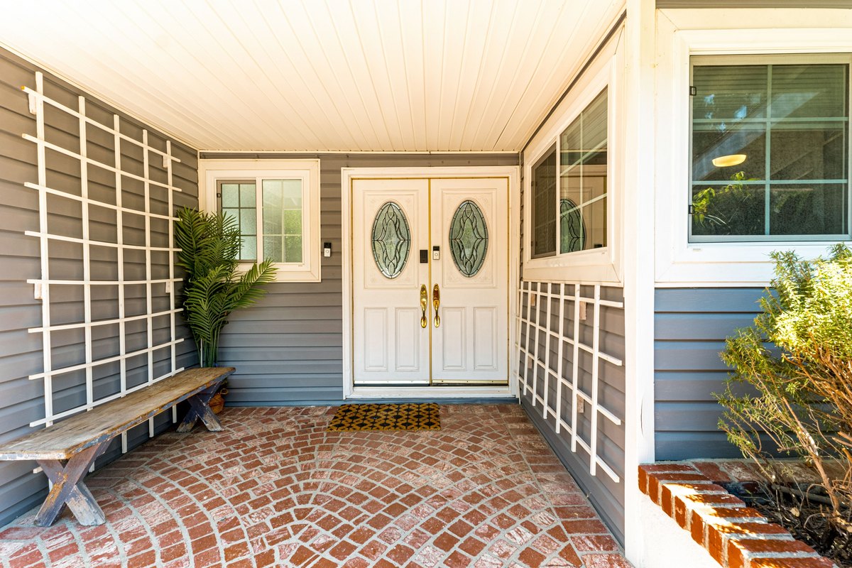 White double front doors with oval leaded-glass panels on a brick paver entry
