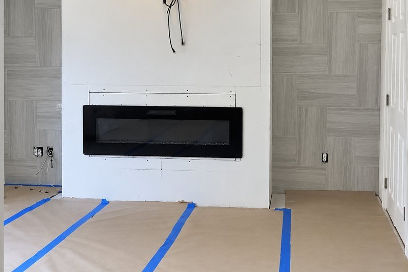 White drywall chase with a recessed fireplace beside gray wood-look wall tile