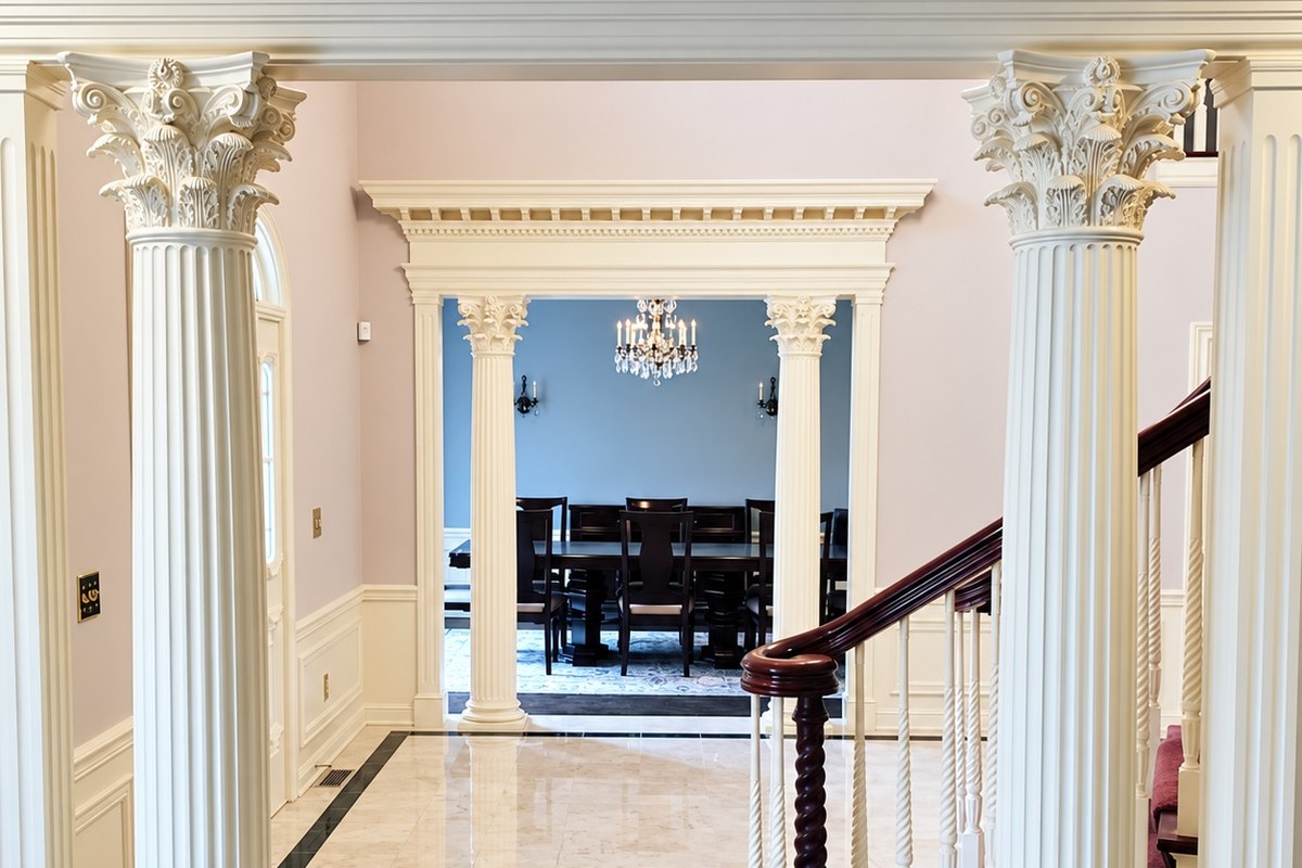 Front hall with white raised-panel wainscoting behind two cream fluted Corinthian columns