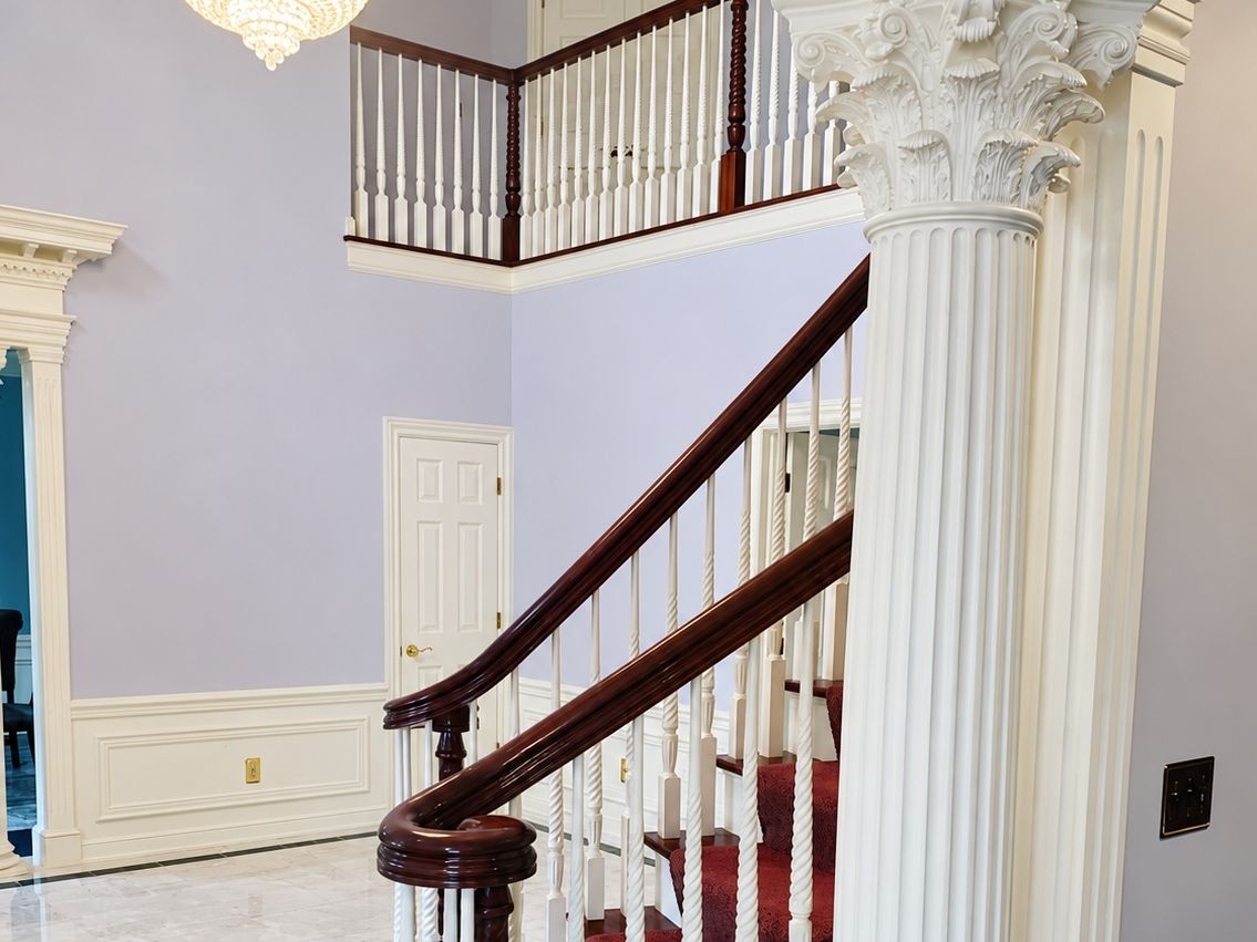 Two-story foyer: staircase with a curved mahogany handrail, white twisted and turned balusters