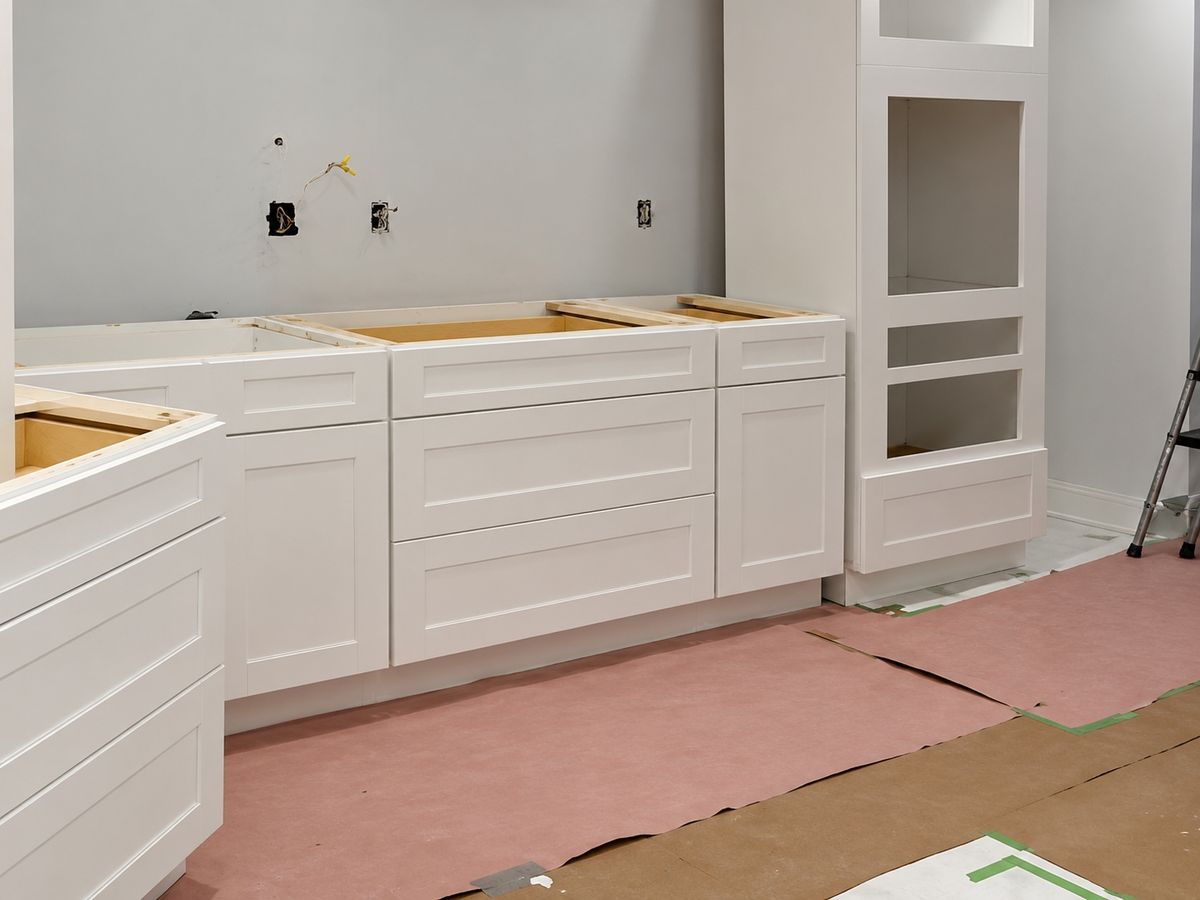 Kitchen mid-install: a run of white shaker base cabinets and drawers with no countertop