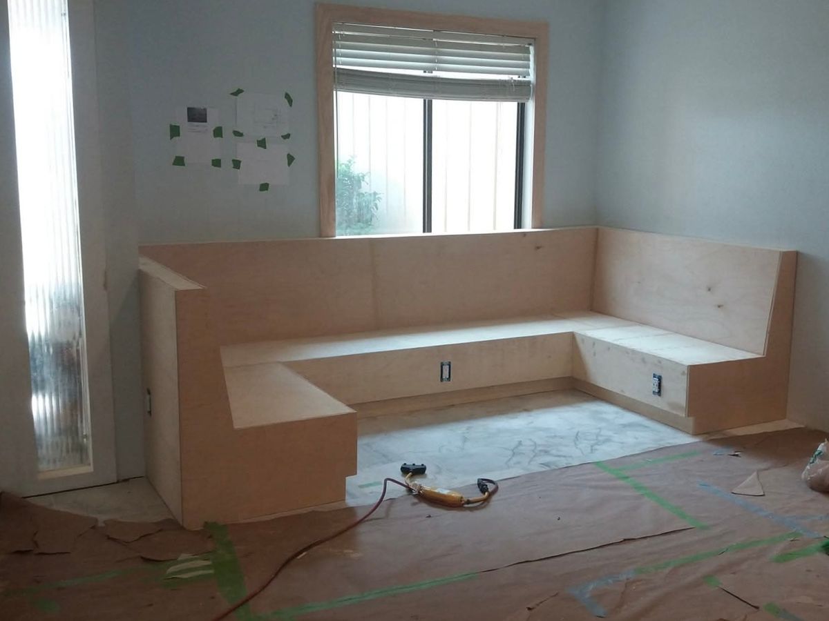 Living room corner with an L-shaped plywood built-in bench seat under a window