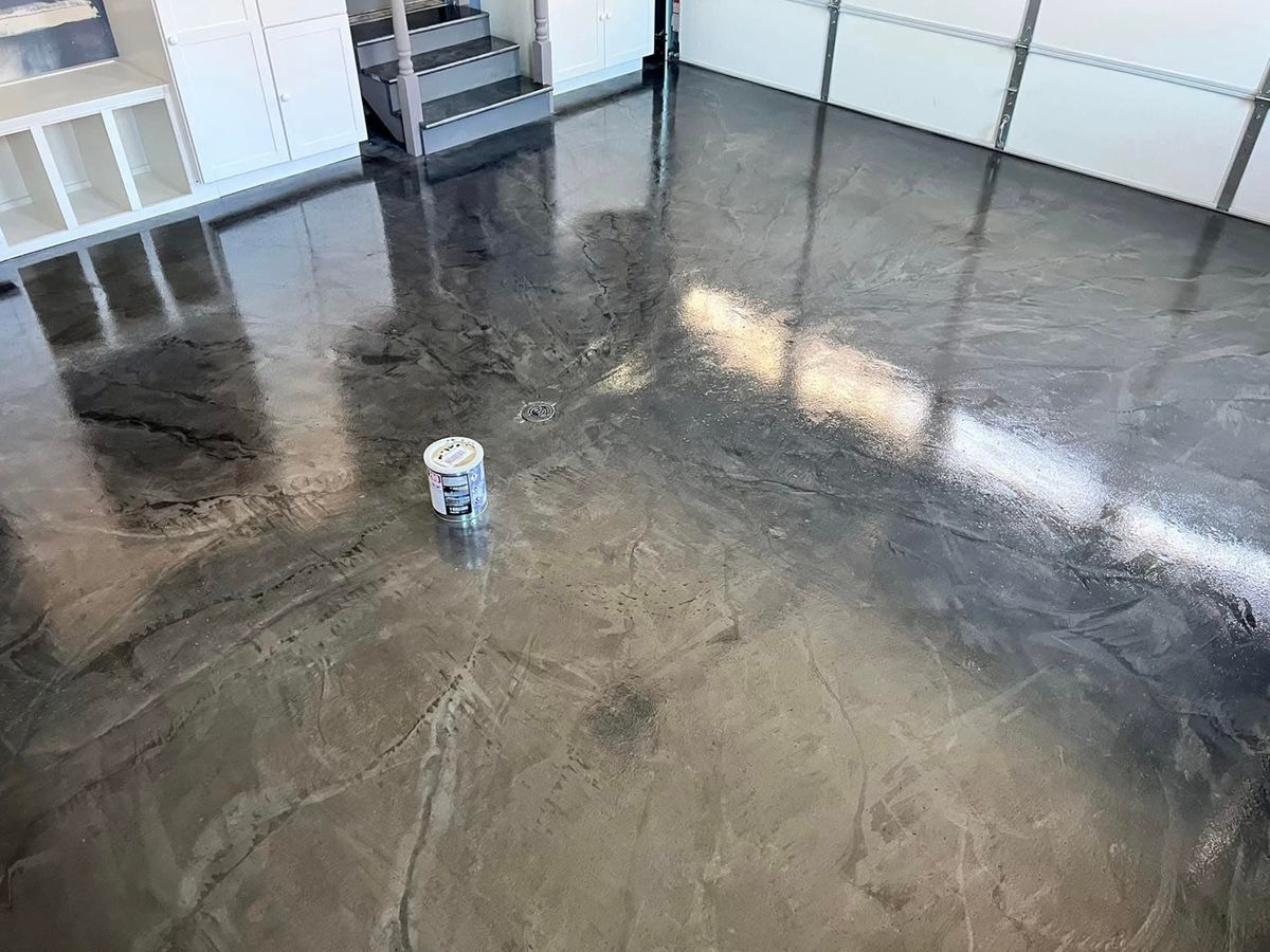 Glossy metallic gray and silver epoxy floor with a floor drain and a small paint can