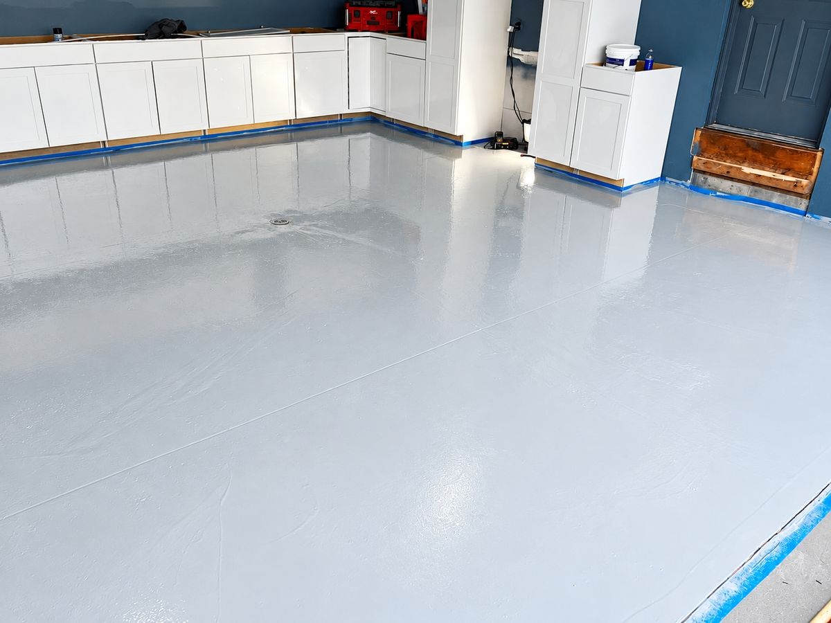 Large room with a smooth glossy light gray epoxy floor, a floor drain