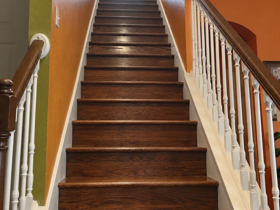 Long straight wood staircase with stained oak treads and risers and white balusters
