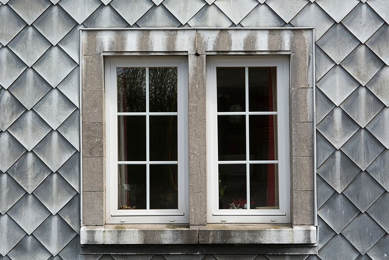 Pair of white six-lite windows in a stone surround on a slate shingle wall